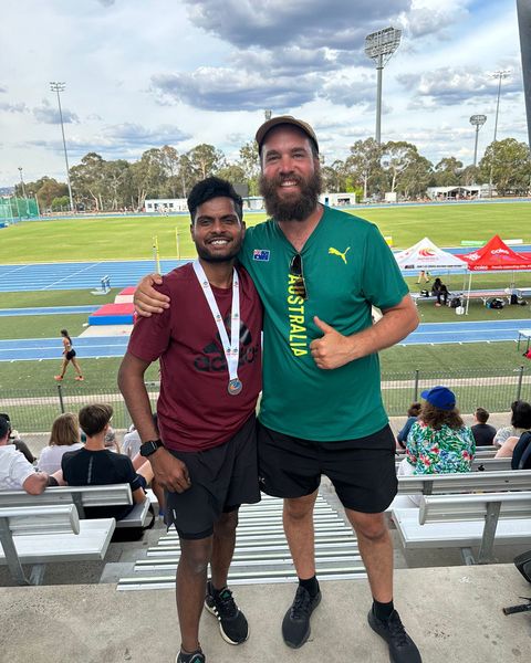 Vijay Kumar with a medal at a track in Australia